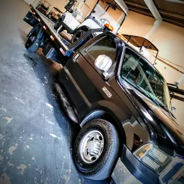 Guincho F-250 carregando veículos dentro de um galpão